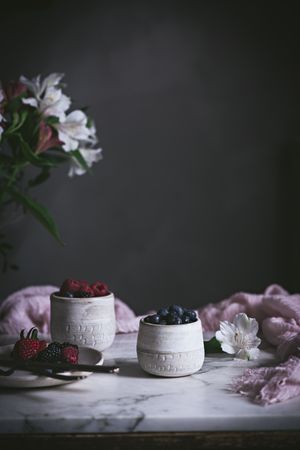 Raspberries and blueberries on glasses on table