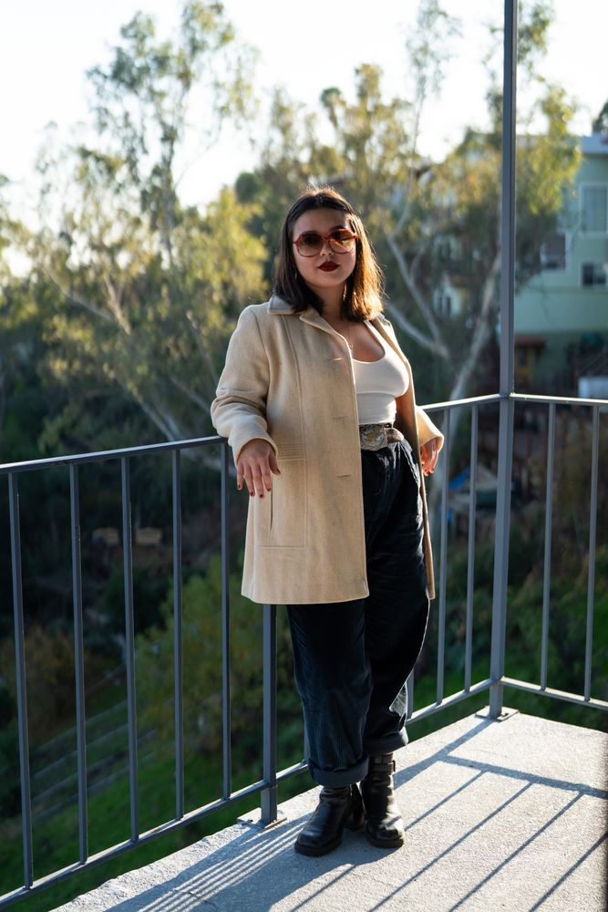 Young woman standing and leaning on patio railing with view behind