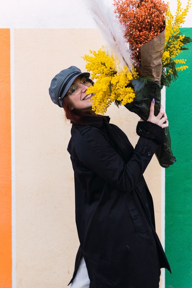 Woman with flowers smiling against colorful wall