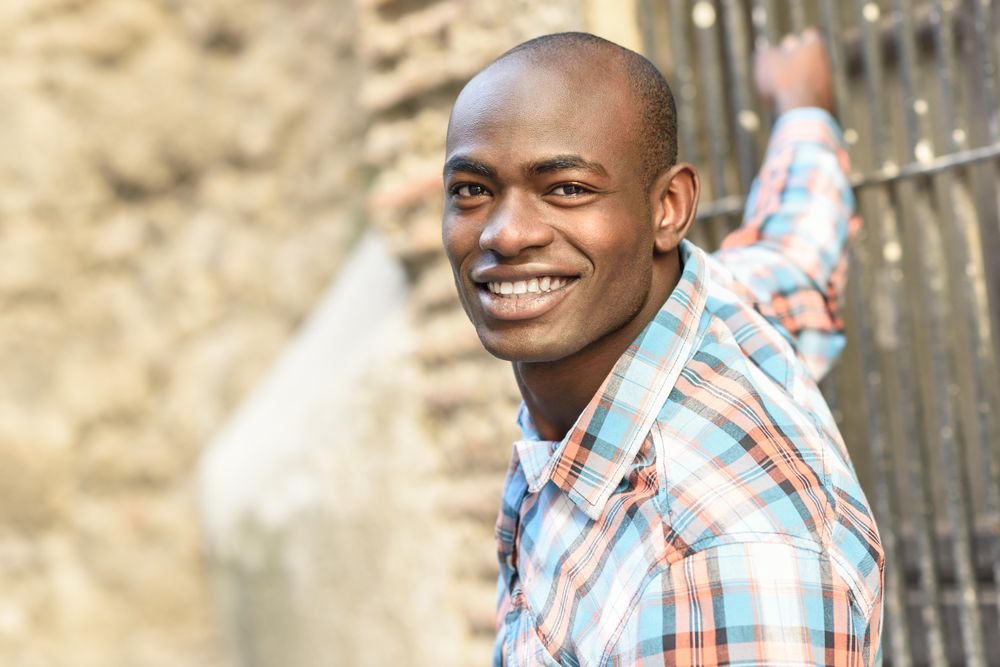 Happy male in plaid shirt leaning off window bars
