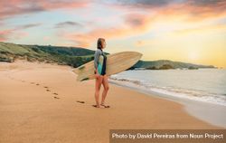 Woman standing on sand with surfboard gazing out at beautiful ocean view 42Bwd4
