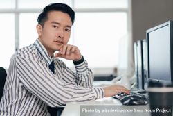 Asian male employee working on computer at desk in the office 4dQAQb