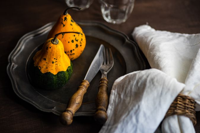 Dark table setting with two squashes and cutlery