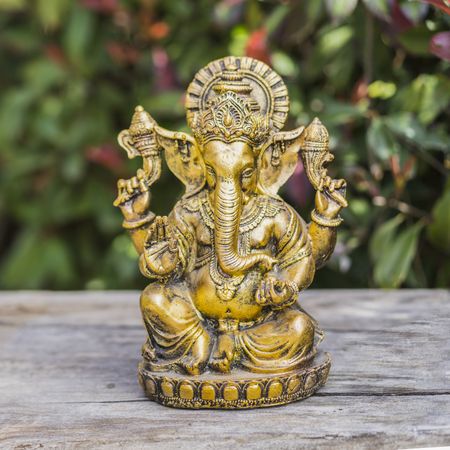 Ganesha statue sitting in meditating yoga pose on a trunk.