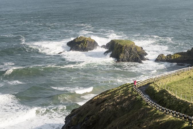 Person walking on country road between sea and field
