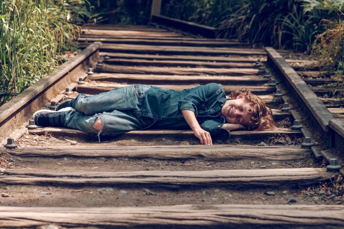 Cheerful boy lying on railroad
