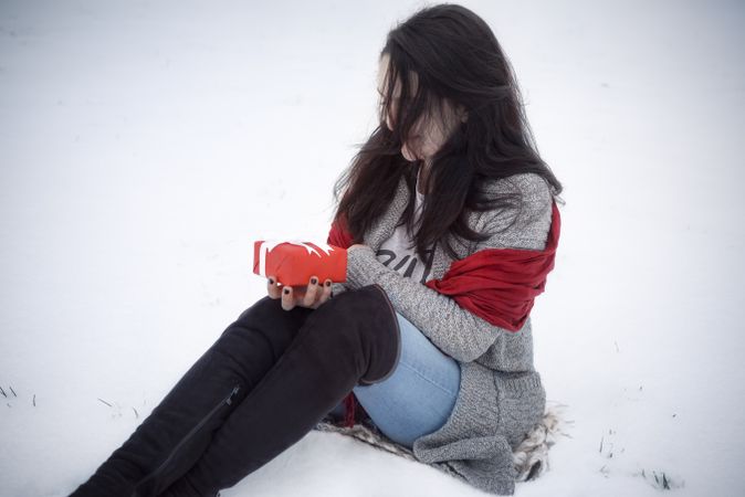 Woman holding gift and sitting on snow
