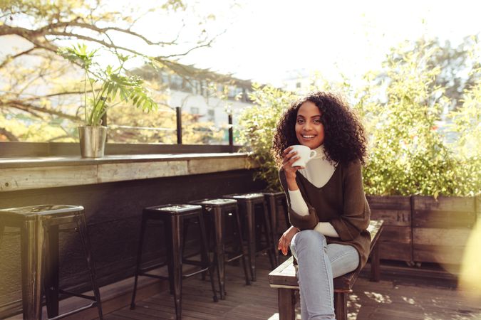 Young woman drinking coffee at a rooftop coffee shop