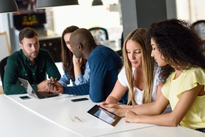 Five male and female colleagues studying with tablet and laptop computer on desk