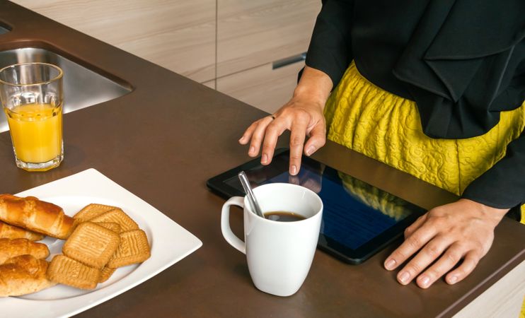 Woman reading news on tablet while having breakfast at home before work