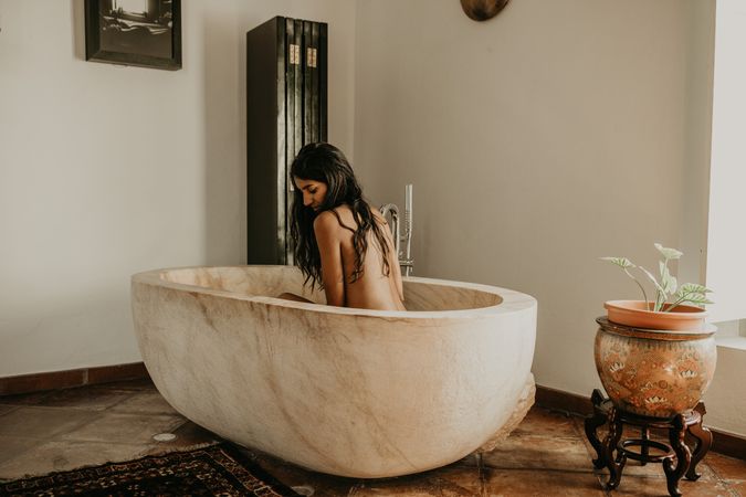 Woman sitting and washing in bath