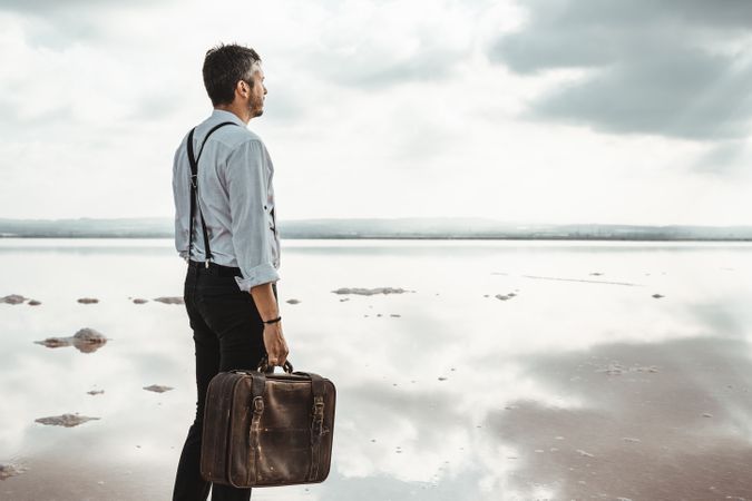 Fancy man with suitcase gazing at seaside