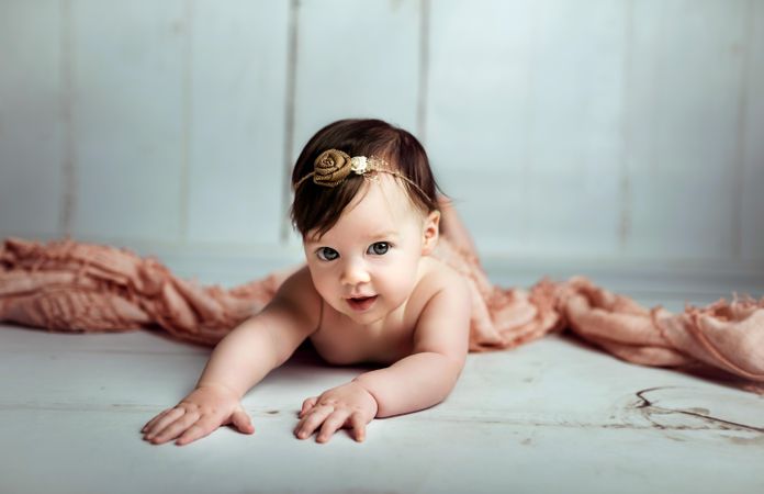 Baby girl on floor beside pink textile