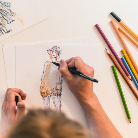 Top view of a fashion designer drawing a fashion sketch.