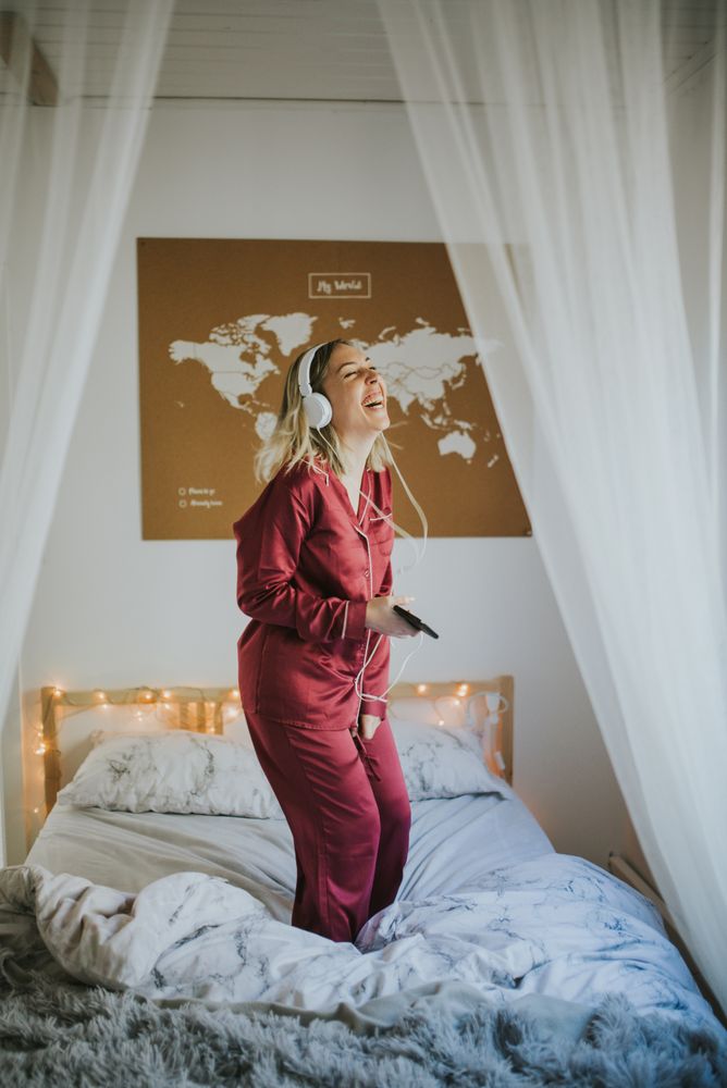 Woman with headphones dancing in bed