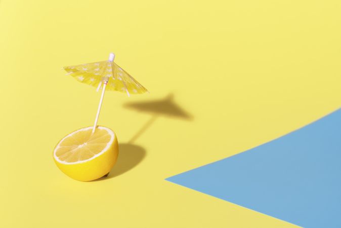 Lemon with a cocktail umbrella in sunlight