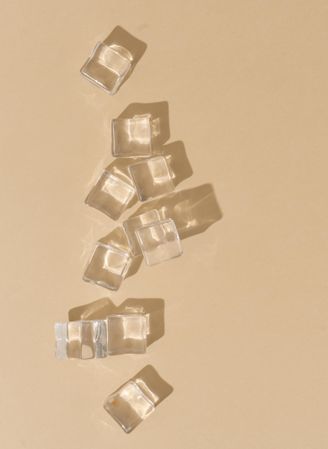 Flat lay of ice cubes on beige background with shadows