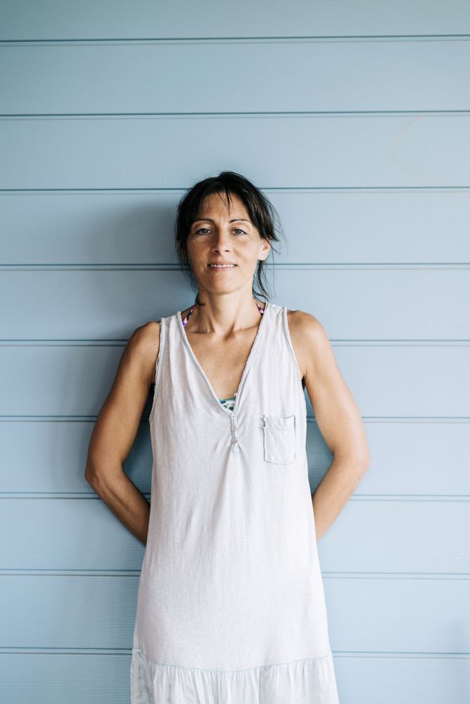 Portrait of wistful woman with ponytail leaning on wood wall in summer dress