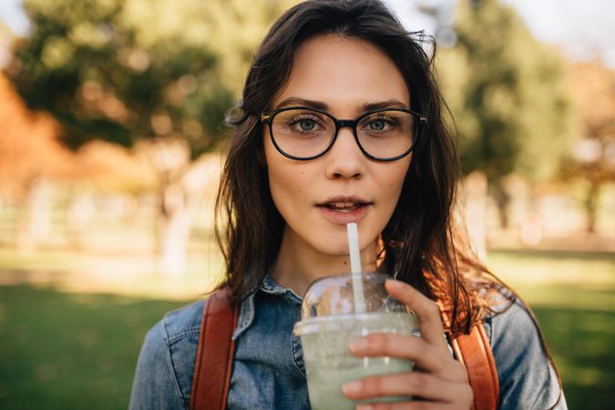 Close up of a young woman at park drinking juice