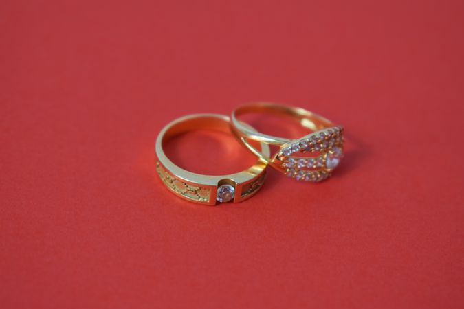 Two diamond gold wedding rings together on red table