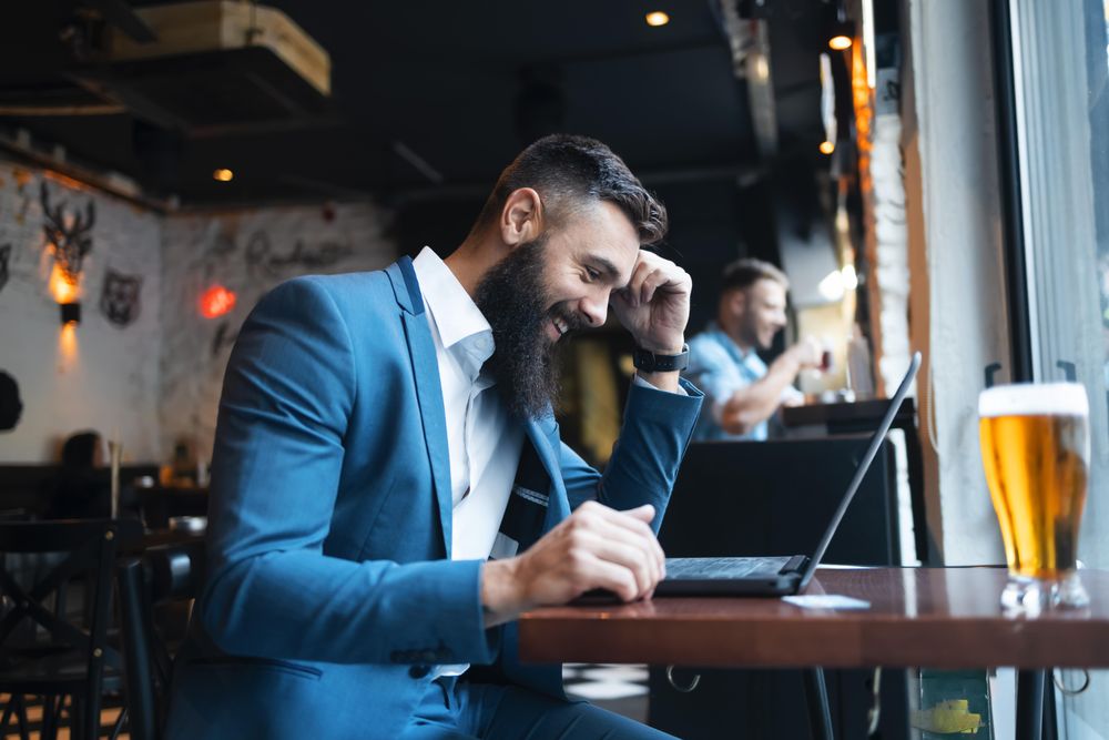Man smiling at laptop during working lunch in a bar