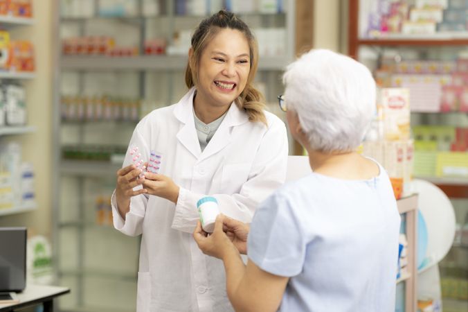 Asian female pharmacist gives Indian woman medicine advice to cure ailments.