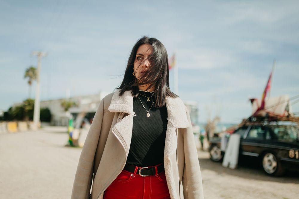 Stylish woman with jacket on beach parking
