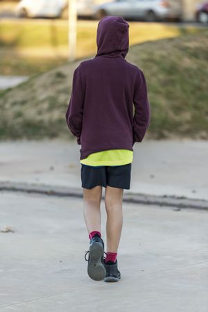 Rear view of a teenage male in hoodie walking away