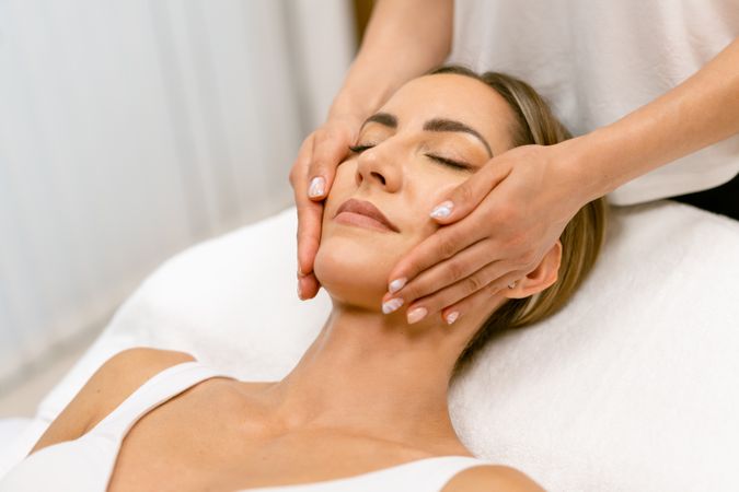 Woman having her face massaged by skilled masseuse