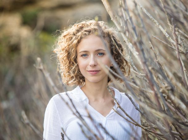 Young woman near dry twigs of bushes