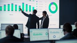 Business Professionals Analyze Data on Large Screen.