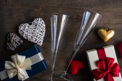 Top view of two glass champagne flutes with gifts and heart ornaments