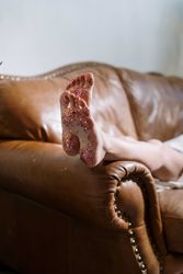 Cropped image of feet with glitter on brown couch 41vJ8b