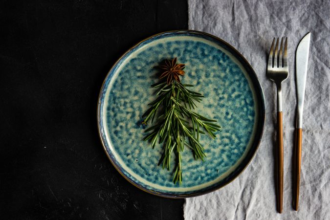 Christmas table setting of blue plate with rosemary sprig in tree shape