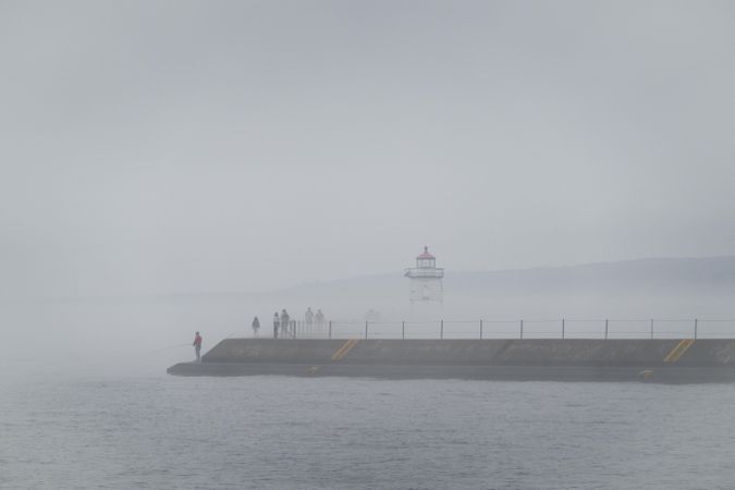 People in the pier in the fog walking to a lighthouse in Two Harbors, Minnesota