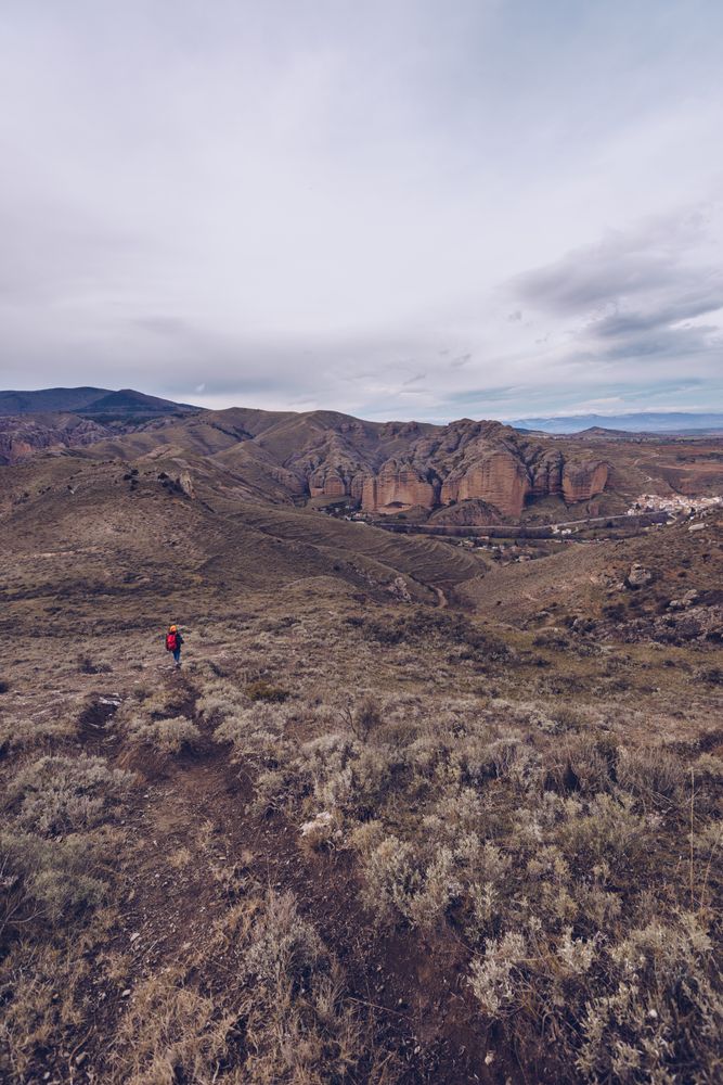 Hiker with backpack walking along rural road to cliff on gloomy day