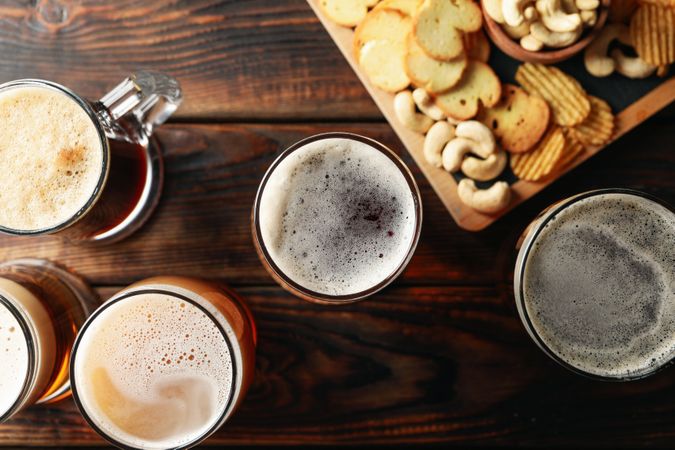 Glasses of beer and snacks on wooden table