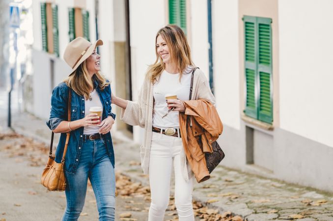 Women walking and chatting with cups of coffee