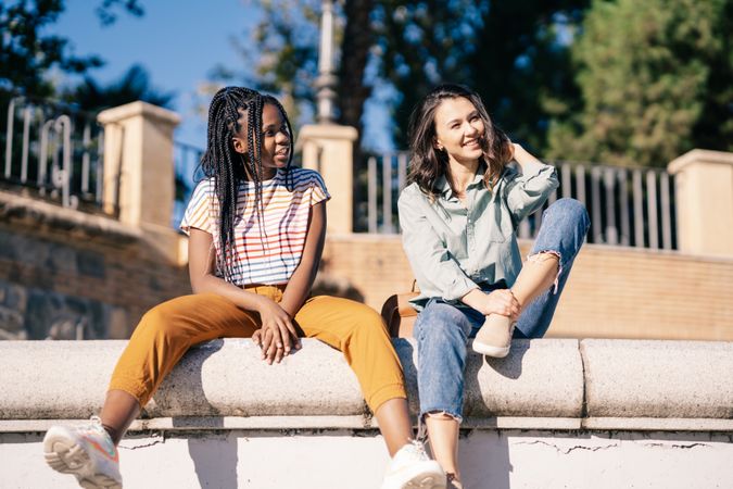 Female friends sitting on outdoor wall