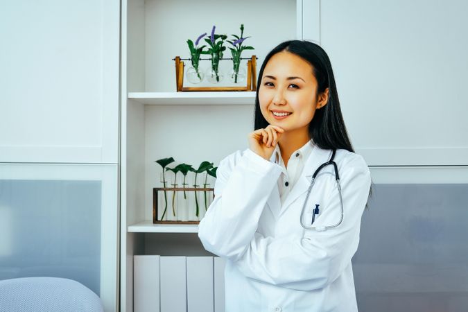 Curious Asian doctor thinking about something in her office