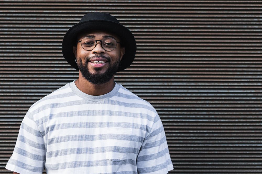 Smiling Black hipster man in hat looking at camera