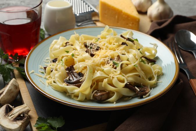 Composition with plate of tasty pasta and ingredients for cooking on gray background