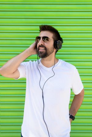Man in headphones and glasses in front of green background