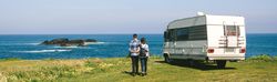 Couple taking a walk near the coast with a camper