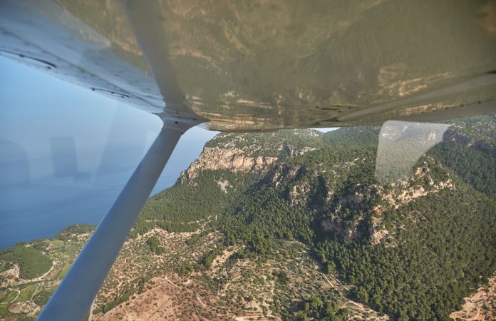 Aircraft view of green mountains and blue sea in sunlight