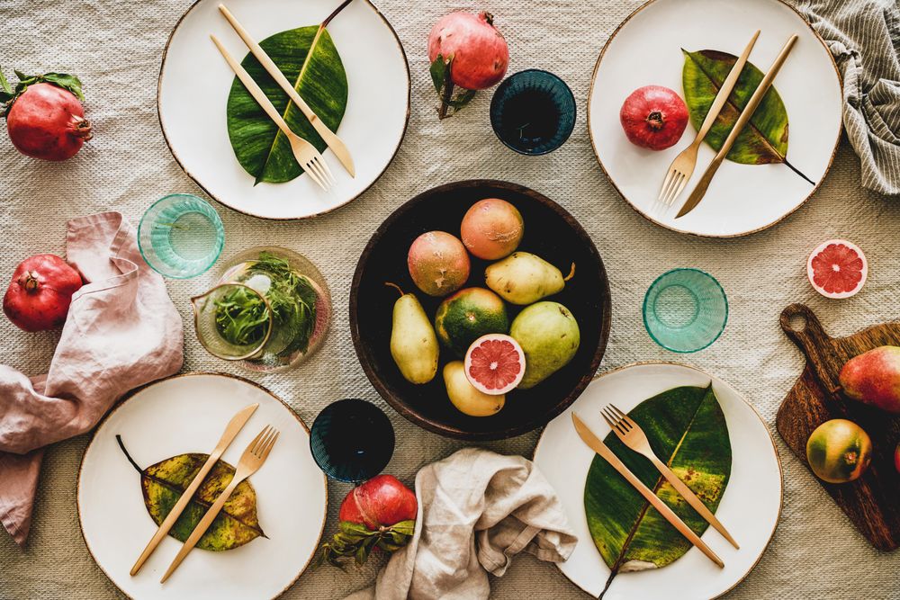 Fresh table setting with leaves on bright plates, pitcher, with fruit bowl