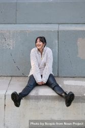 Woman smiling and sitting on gray concrete floor 56yPz0