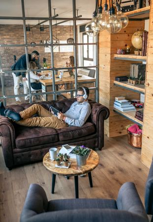 Businessman lying on an office sofa with tablet