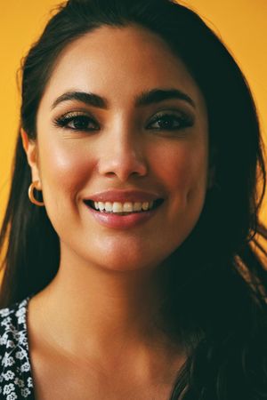 Headshot of happy Hispanic woman in yellow room, vertical