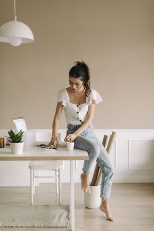 Barefoot woman sitting on table looking down at a journal
